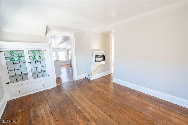 unfurnished living room with heating unit, baseboards, and hardwood / wood-style flooring