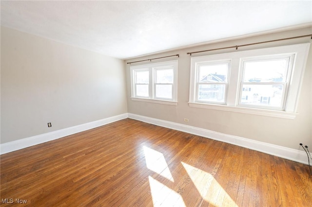 spare room with baseboards and hardwood / wood-style floors