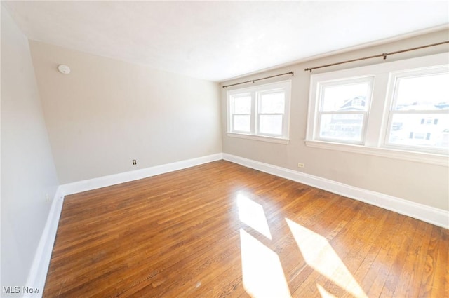 spare room with baseboards and light wood finished floors