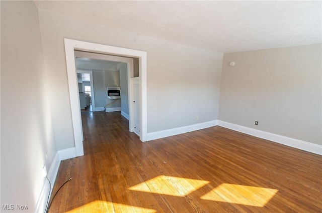 empty room featuring baseboards, heating unit, and hardwood / wood-style floors