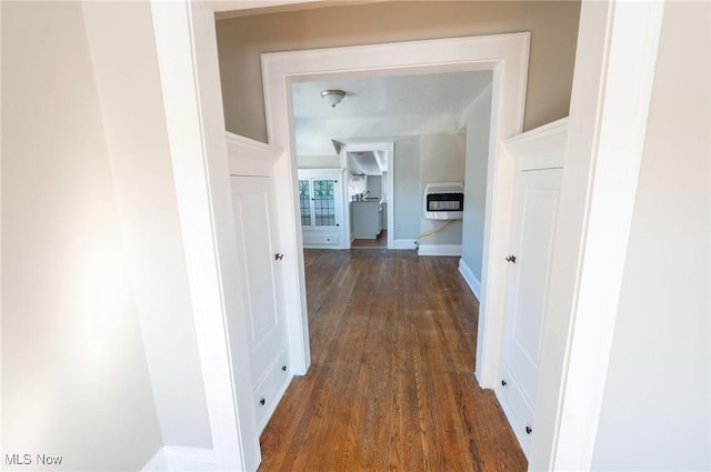 corridor with dark wood-type flooring, heating unit, and baseboards