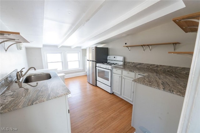 kitchen with open shelves, white gas range oven, a sink, freestanding refrigerator, and light wood-type flooring