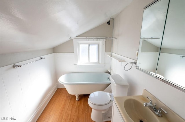 bathroom featuring vanity, wood finished floors, toilet, a soaking tub, and vaulted ceiling