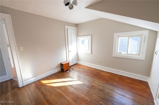 unfurnished bedroom with wood-type flooring, baseboards, and lofted ceiling