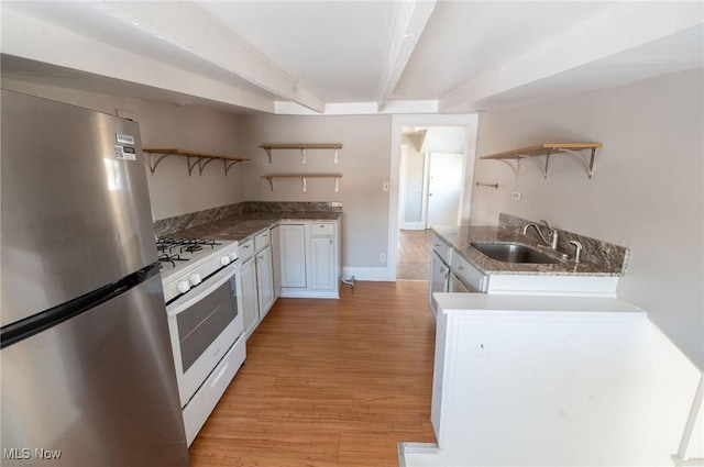 kitchen with open shelves, gas range gas stove, light wood-type flooring, a sink, and freestanding refrigerator