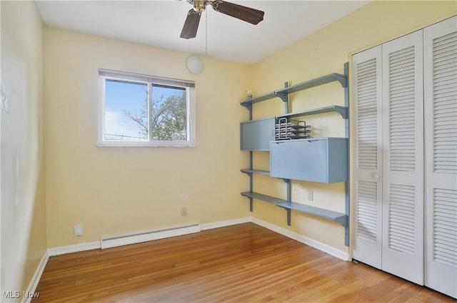 unfurnished bedroom featuring a closet, baseboards, wood finished floors, and a baseboard radiator