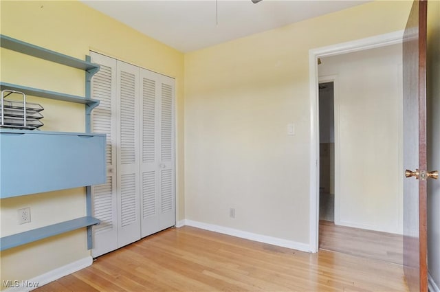 unfurnished bedroom with baseboards, light wood finished floors, and a closet
