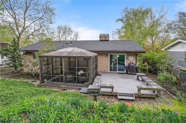 rear view of house featuring fence, a shingled roof, a sunroom, a deck, and a chimney
