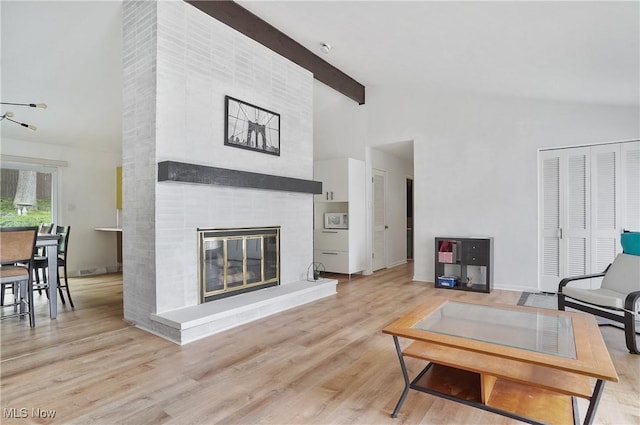 living room featuring wood finished floors, a tile fireplace, high vaulted ceiling, and beamed ceiling