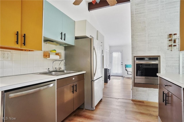 kitchen with ceiling fan, appliances with stainless steel finishes, light wood-type flooring, light countertops, and a sink