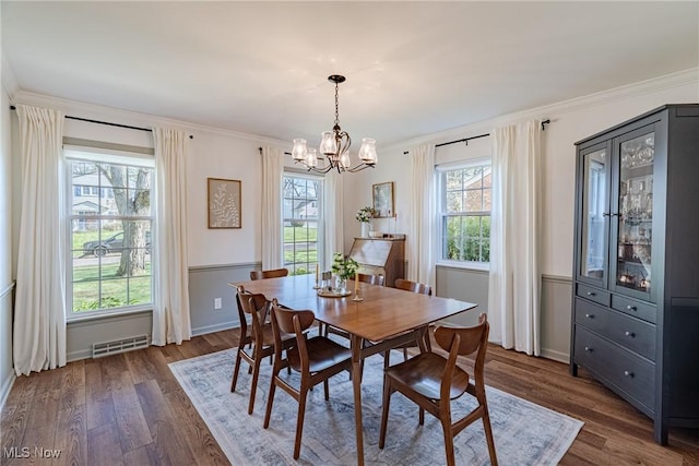 dining room featuring a notable chandelier, visible vents, dark wood-style floors, and ornamental molding