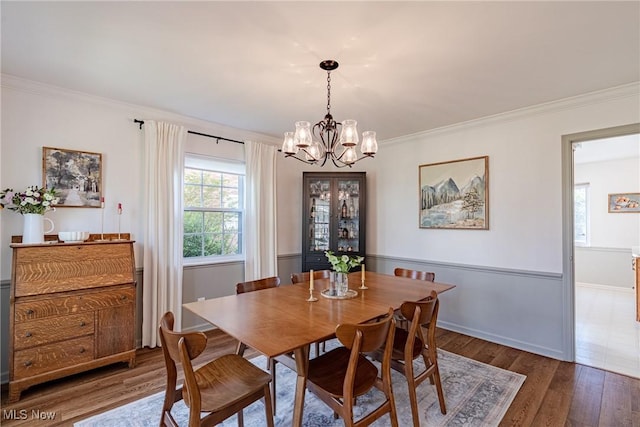 dining room featuring an inviting chandelier, baseboards, crown molding, and wood finished floors