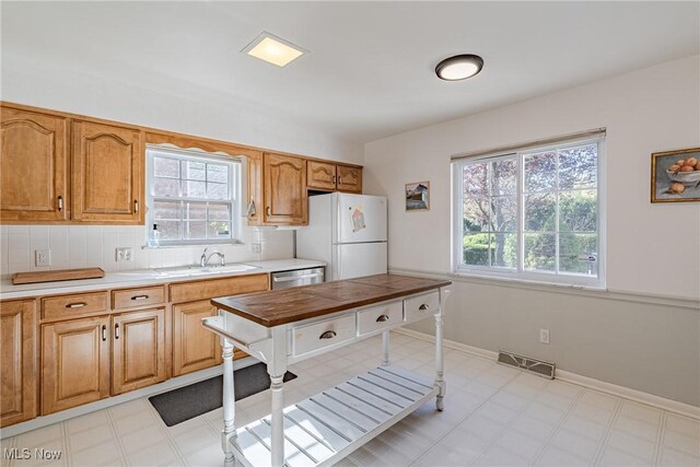 kitchen with visible vents, freestanding refrigerator, a sink, and a healthy amount of sunlight