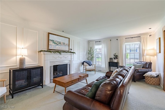 living area with carpet flooring, a decorative wall, a fireplace, and ornamental molding