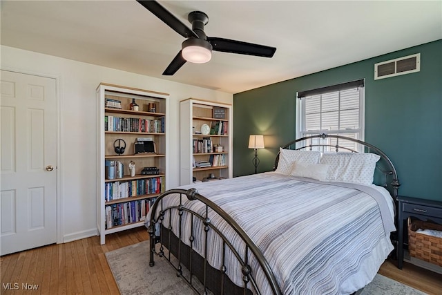 bedroom featuring visible vents, baseboards, ceiling fan, and hardwood / wood-style floors