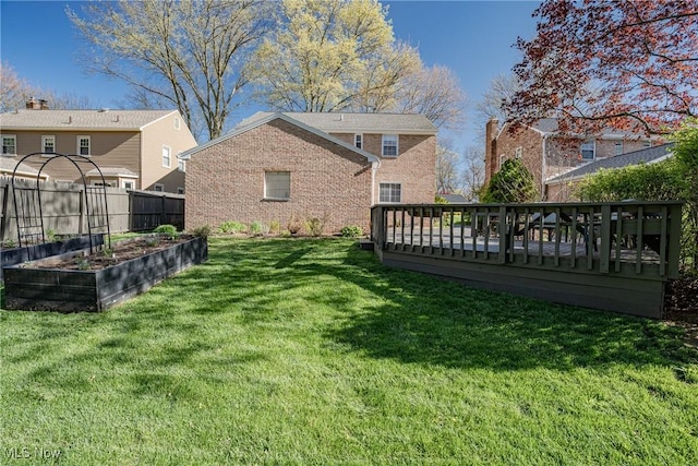 view of yard with fence, a wooden deck, and a vegetable garden
