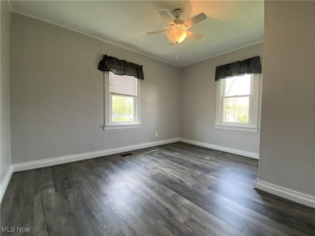 unfurnished room with baseboards, ornamental molding, ceiling fan, and dark wood-style floors