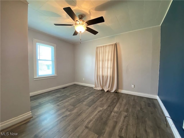 empty room featuring baseboards, ornamental molding, a ceiling fan, and dark wood finished floors