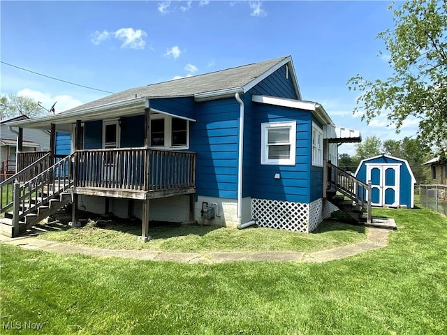 rear view of property with stairs, an outbuilding, a yard, and a shed