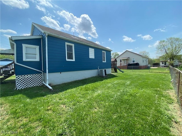view of property exterior with a lawn, fence, and central air condition unit