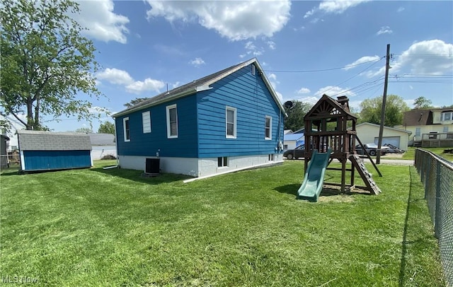rear view of house featuring a lawn, a playground, fence, and a storage shed