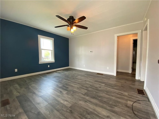 spare room featuring baseboards, ceiling fan, dark wood finished floors, and visible vents