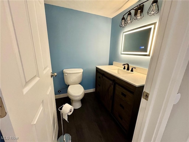 bathroom featuring vanity, baseboards, toilet, and wood finished floors