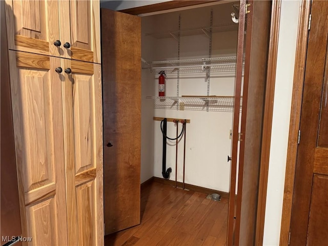 laundry area with laundry area, baseboards, and wood finished floors