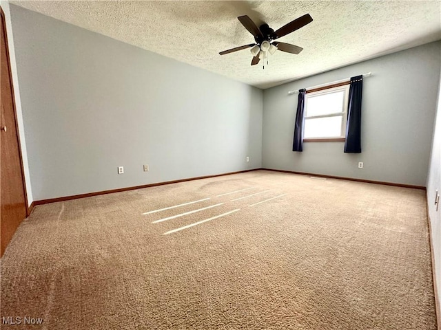 carpeted empty room with baseboards, ceiling fan, and a textured ceiling