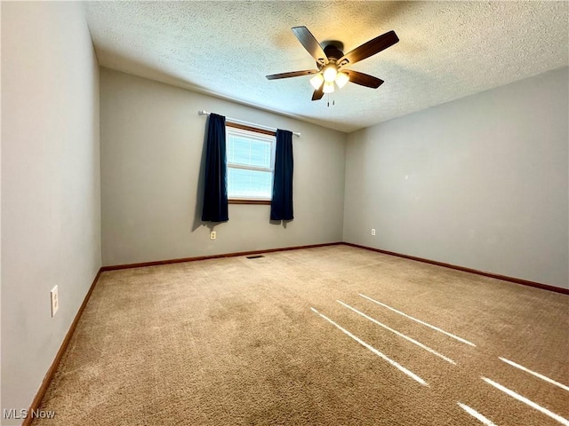 spare room featuring carpet flooring, a ceiling fan, a textured ceiling, and baseboards