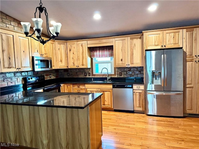 kitchen with a chandelier, appliances with stainless steel finishes, a sink, and tasteful backsplash