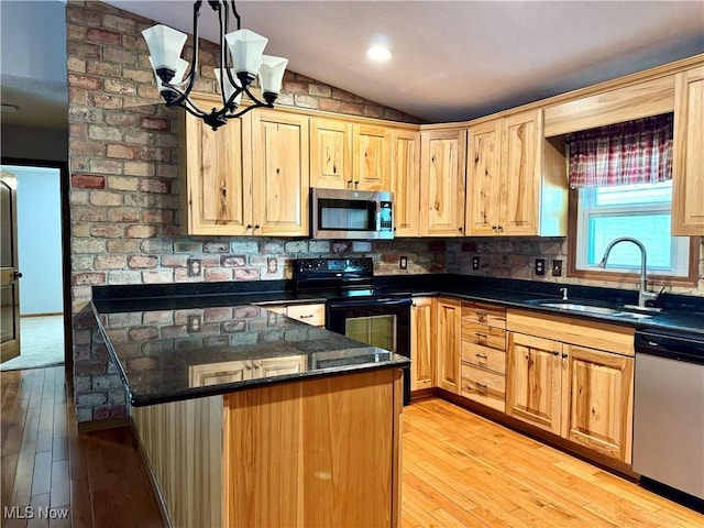 kitchen with a sink, light wood finished floors, appliances with stainless steel finishes, a notable chandelier, and vaulted ceiling