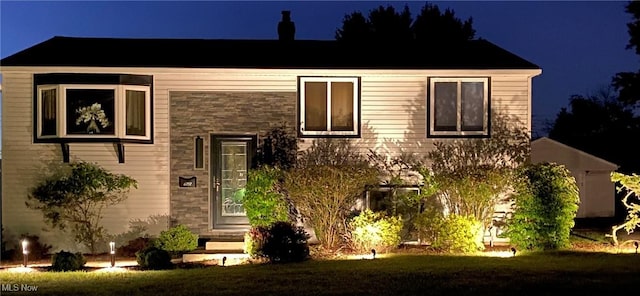 bi-level home with a yard and stone siding