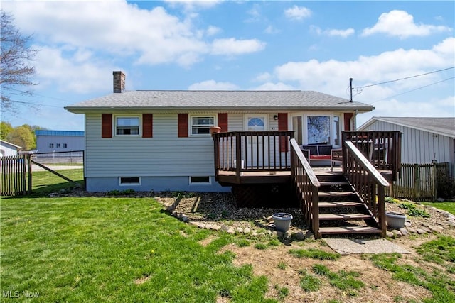 back of house featuring a lawn, a chimney, fence, and a wooden deck