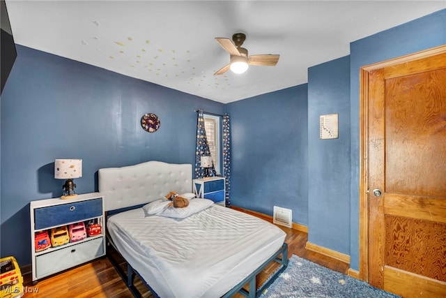 bedroom with a ceiling fan, baseboards, and wood finished floors