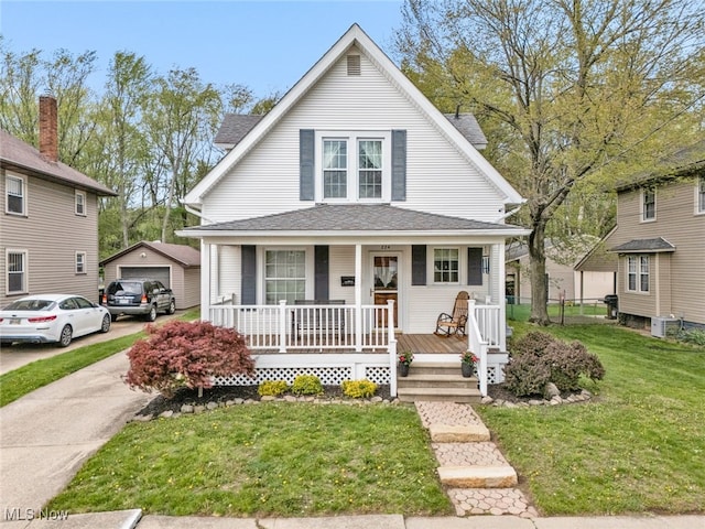 bungalow-style house with a detached garage, a front yard, an outbuilding, concrete driveway, and covered porch