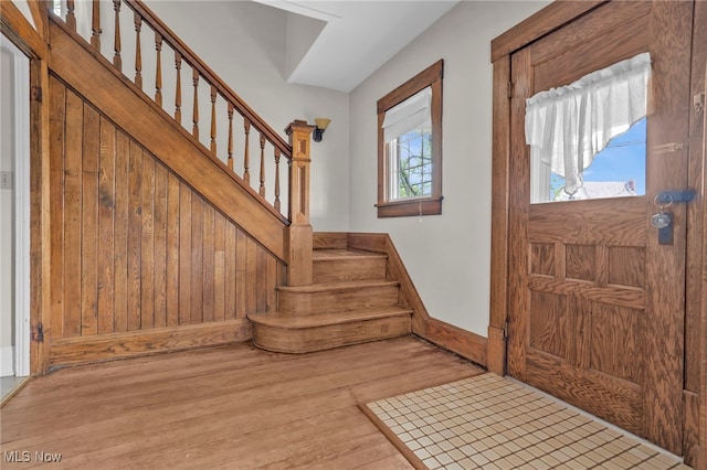 entrance foyer with baseboards, wood finished floors, and stairway
