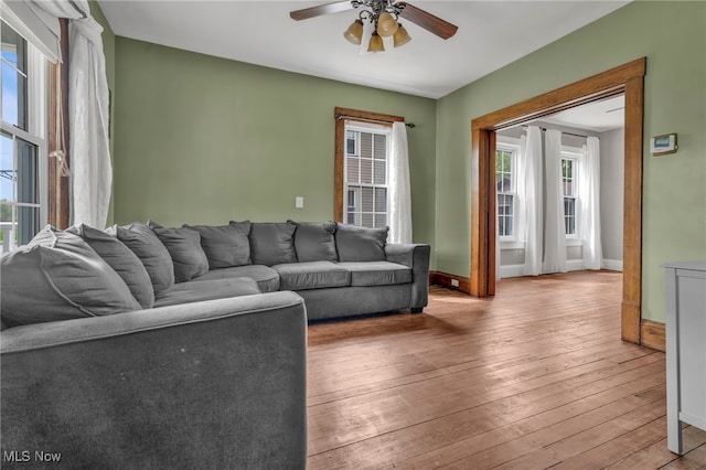 living area featuring plenty of natural light, a ceiling fan, baseboards, and hardwood / wood-style flooring