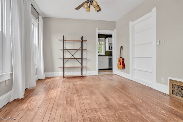 empty room with baseboards, ceiling fan, light wood-type flooring, and visible vents