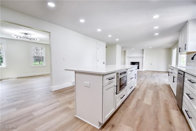 kitchen with light countertops, open floor plan, light wood-type flooring, and a fireplace