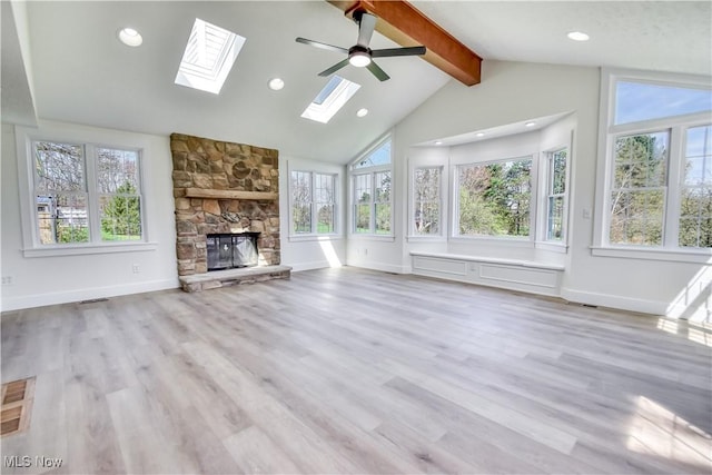 unfurnished living room featuring a healthy amount of sunlight, a skylight, a fireplace, and beam ceiling