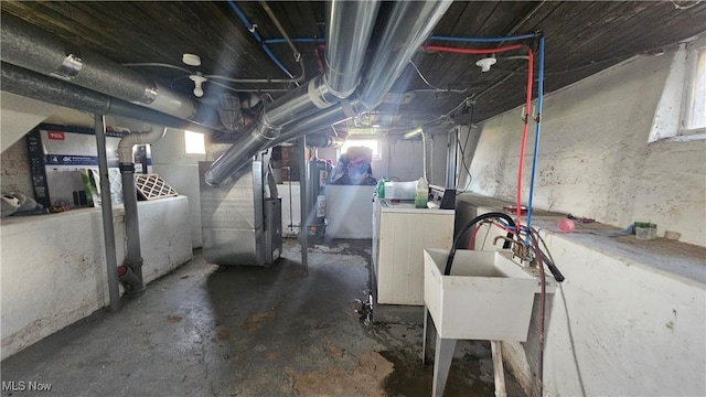 below grade area with heating unit, water heater, a sink, and washer and clothes dryer