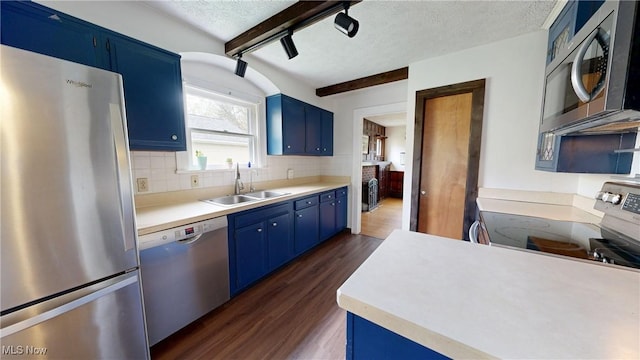 kitchen with a sink, appliances with stainless steel finishes, blue cabinetry, and dark wood-type flooring