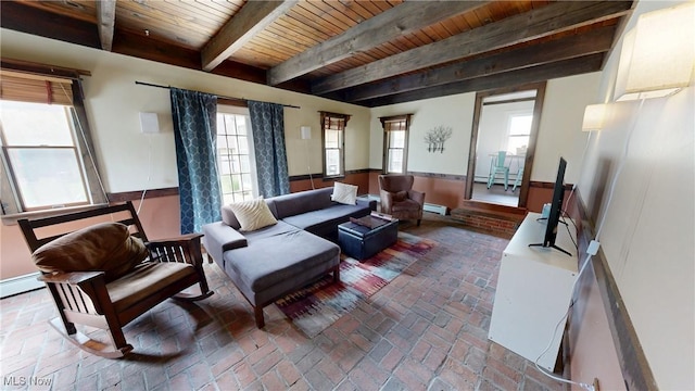 living area featuring a healthy amount of sunlight, wooden ceiling, a baseboard radiator, and brick floor