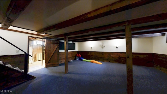 finished basement featuring carpet floors, wood walls, wainscoting, and stairs