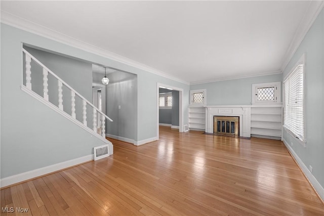 unfurnished living room with crown molding, baseboards, stairs, and light wood-style flooring