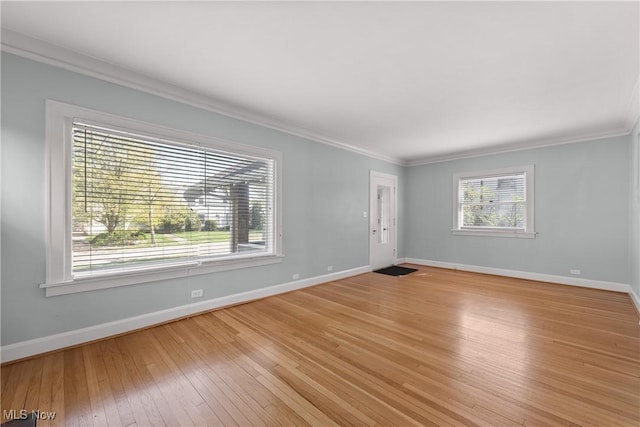 unfurnished living room featuring crown molding, baseboards, and light wood-type flooring