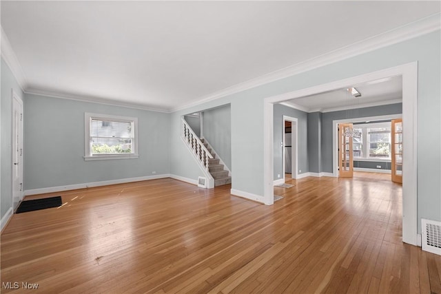 unfurnished living room featuring baseboards, light wood finished floors, a wealth of natural light, and stairway
