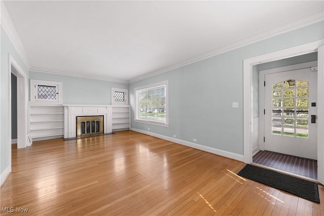 unfurnished living room with crown molding, light wood finished floors, baseboards, and a healthy amount of sunlight