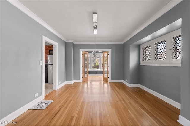 unfurnished dining area with visible vents, ornamental molding, light wood-style flooring, and baseboards